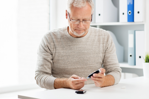 Middle aged man checking his blood glucose levels while seated in an office